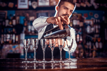 Focused bartending intensely finishes his creation at the bar counter