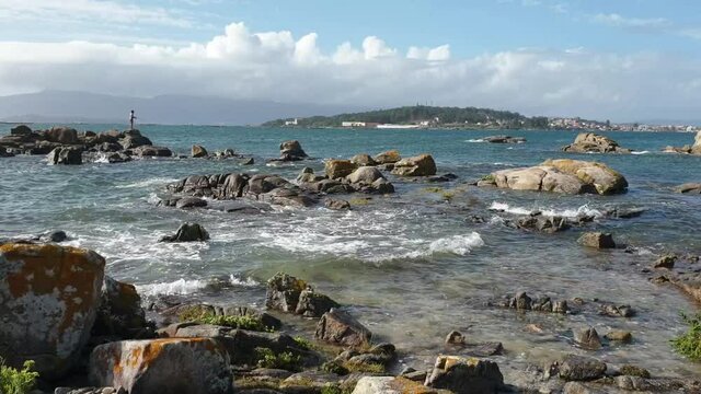 Waves between the coastal rocks with a angler on top in Arruda cape, Arousa Island, Galicia, Spain