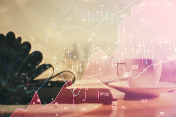 Double exposure of financial chart drawing and desktop with coffee and items on table background....