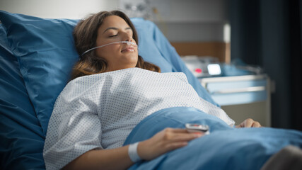 Medical Hospital Ward: Beautiful Latin Woman with Nasal Cannula is Resting on a Bed. Recovering after Successful Surgery Female Patient Sleeping and Gettin Well. Modern High Tech Equipped Room