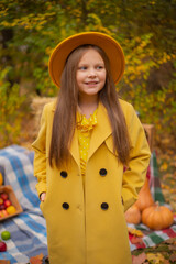 cute beautiful teenage brunette girl in an orange hat, dress and coat next to autumn decorations - pumpkins, apples, blankets, hay. Cosiness