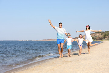 Happy family walking on sandy beach near sea. Summer holidays