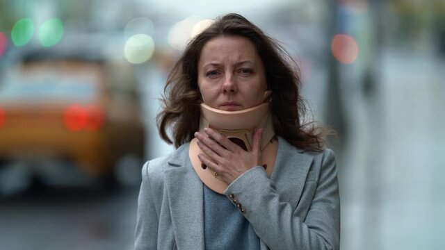 sad woman with neck ache is walking on city street, wearing orthopedic collar, curing of osteochondrosis