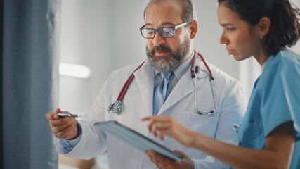 Modern Hospital Ward: Experienced Latin Doctor Talks With Professional Head Nurse. They Use...