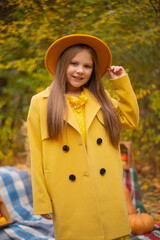 cute beautiful teenage brunette girl in an orange hat, dress and coat next to autumn decorations - pumpkins, apples, blankets, hay. Cosiness