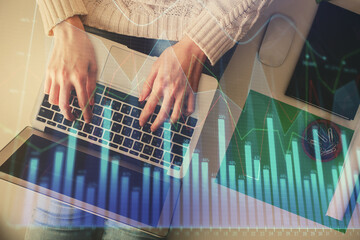 Double exposure of woman hands working on computer and forex chart hologram drawing. Top View. Financial analysis concept.