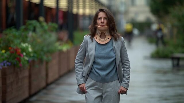 adult lady is walking in city, wearing cervical collar for curing injury of neck, illness of spinal