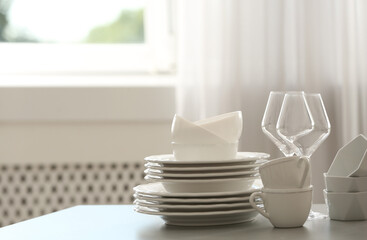 Set of clean dishware and wineglasses on table indoors. Space for text