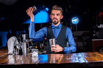 Focused bartending decorates colorful concoction while standing near the bar counter in bar