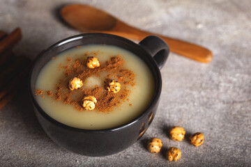 Boza or Bosa, traditional Turkish drink with roasted chickpea in ceramic bowl with cinnamon on stone background. 