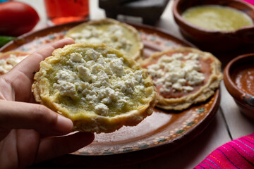 Mexican picaditas with sauce and fresh cheese on white background