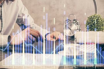 Double exposure of man's hands holding and using a phone and financial graph drawing. Analysis concept.