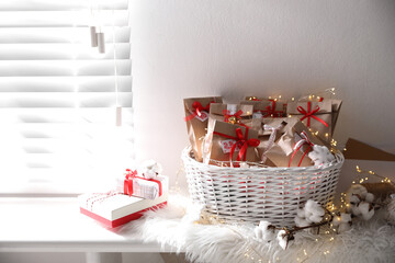 Set of gifts in basket and Christmas decor on window sill indoors. Advent calendar