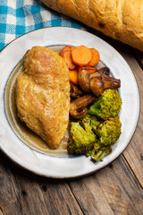 Chicken in mustard sauce with roasted vegetables in wooden background