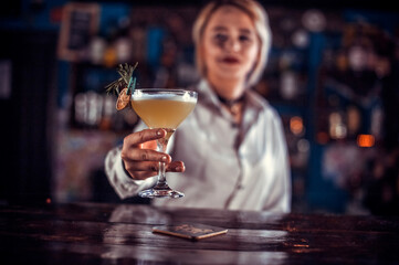 Pretty girl bartending decorates colorful concoction at the nightclub