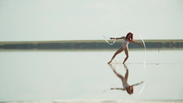 Rhythmic gymnastics outdoors in the sea, woman is dancing in the water, 4k