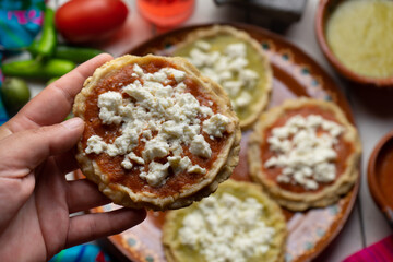 Mexican picaditas with sauce and fresh cheese on white background