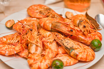 Red cooked prawns on a white plate with vegetables.