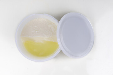 Layer of whey protein formed on top of packaged yogurt after opening in white background.