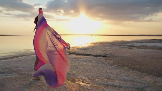 Woman in a bathing suit is dancing and posing on the beach with her pareo, 4k