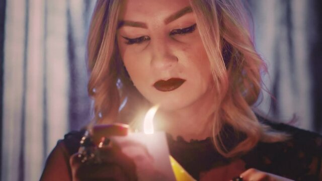 Witch fortune teller psychic moves candle near photo with lost person, and then dripping paraffin on it