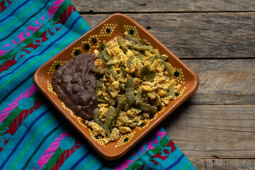 Fototapeta na wymiar Mexican scrambled eggs with nopal cactus and beans on wooden background