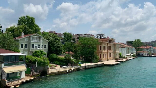 Footage of luxury houses in upscale neighborhood called "Anadolu Hisari" by Bosphorus in Istanbul. It is a beautiful summer scene on cloudy summer day. Camera moves forward.