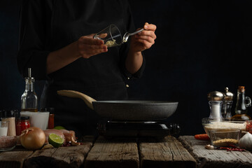 Professional chef pours rice into pan with chicken fillet. Backstage of cooking traditional Indian chicken curry on dark blue background. Frozen motion. Concept cooking process. Frozen motion.