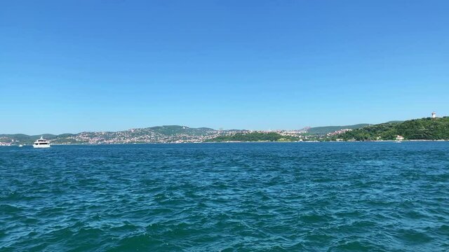 Footage of boats passing on Bosphorus strait in Tarabya area of Istanbul. Kanlica / Beykoz area of Asian side is in the view. It is a sunny summer day. Camera pans right.