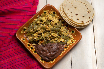 Mexican scrambled eggs with nopal cactus and beans on white background