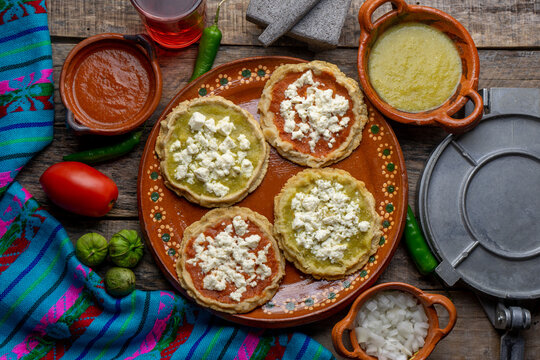 Mexican picaditas with sauce and fresh cheese on wooden background