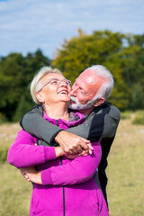 Elderly couple embracing in autumn park. Enjoying in love.