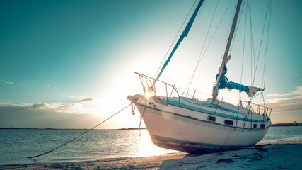 Beached boat or Sunken sailboat. Low tide of the ocean. After Tropical storm or Hurricane. Florida Hurricane. Seascape sunset on background. 