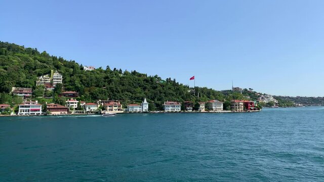 Footage of yacht passing in Anadolu hisari / Kandilli area of Istanbul on Bosphorus strait. Beautiful scene. It is a sunny summer day. Camera moves forward.