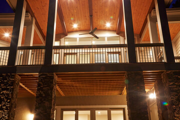 Exterior of contemporary home of two story porch at night with interior lights doing the natural lighting