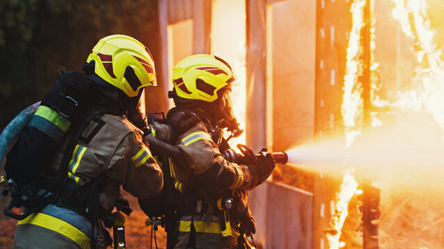 Fireman extinguish fire with the hose. Burning house fire drill. High quality photo