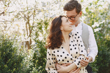 Man and woman in blooming garden on spring day. Couple in love spend time in spring garden. Flowers...