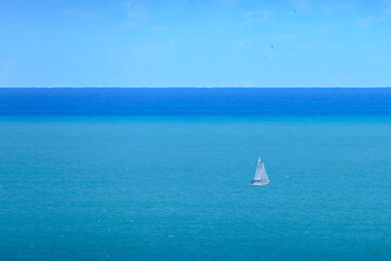 Minimalist: white sailboat in turquoise and blue seas