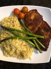 Fried chicken cutlet with asparagus and yellow rice dinner plate