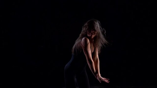 young dancer woman is performing contemporary dance in dark studio, moving energetic and passionately