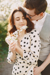 Man and woman in blooming garden on spring day. Couple in love spend time in spring garden. Flowers on background.