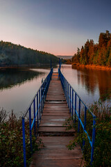 Wooden pier on the lake. Bozcaarmut lake in Bilecik Turkey in the sunny autumn early morning. Vertical landscape.
