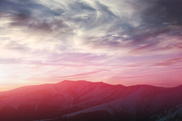 Fototapeta na wymiar Panoramic view of snowy mountain peaks in winter at sunset.