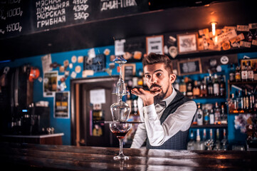 Portrait of barkeeper pouring fresh alcoholic drink into the glasses in the pub