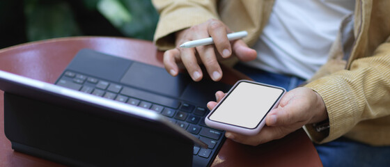 Male hands using smartphone on coffee table in garden