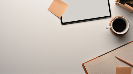 Workspace with tablet, notebook, coffee cup and copy space on white table