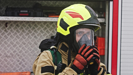 Naklejka premium Close up, portrait of firefighter wearing gas mask in front of the burning house. High quality photo