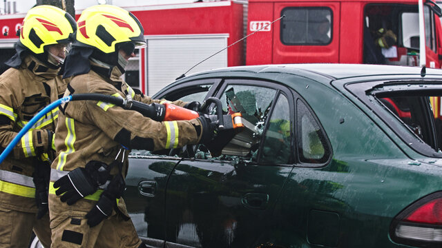 Firefighter beraking glass using jaws of life to extricate trapped victim from the car. High quality photo