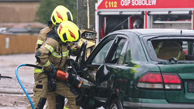 Firefighter beraking glass using jaws of life to extricate trapped victim from the car. High quality photo