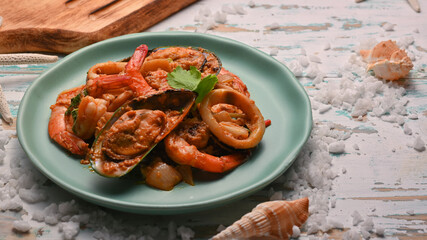 Close up view of seafood stir-fried curry powder on green ceramic plate, Thai food
